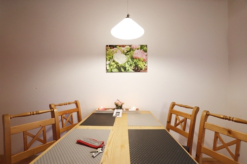 Esstisch der Ferienwohnung Waldblick mit Leinwandbild an der Wand, das den Pfingsrostenkranz aus der Gartendeko von Ferienwohnungen Enders zeigt